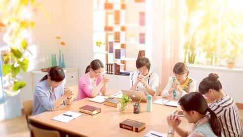 幾個姊妹圍坐在一起禱告神，桌子上有神的話語