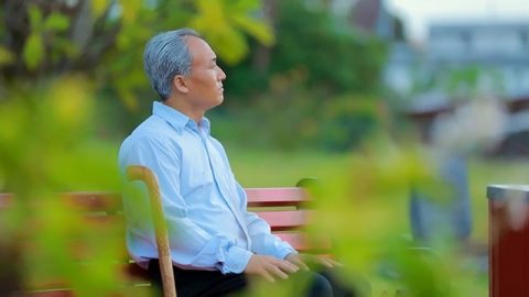 一位老年人坐在公園的長椅上思考