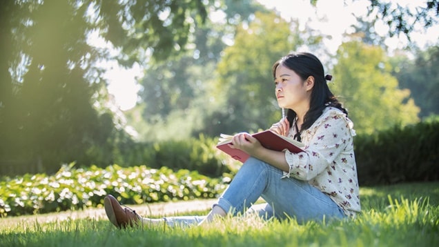 坐在草地上拿着書本思考問題